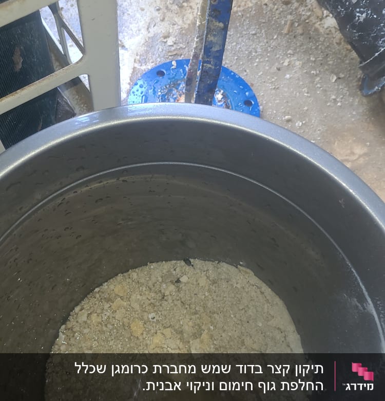 מיכל מתכת עם משקעי אבנית ומים בתחתית